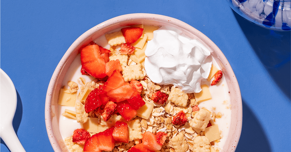 mymuesli Bio Strawberry Cheesecake Müsli in Schale mit Milch, Sahne und frischen Erdbeeren
