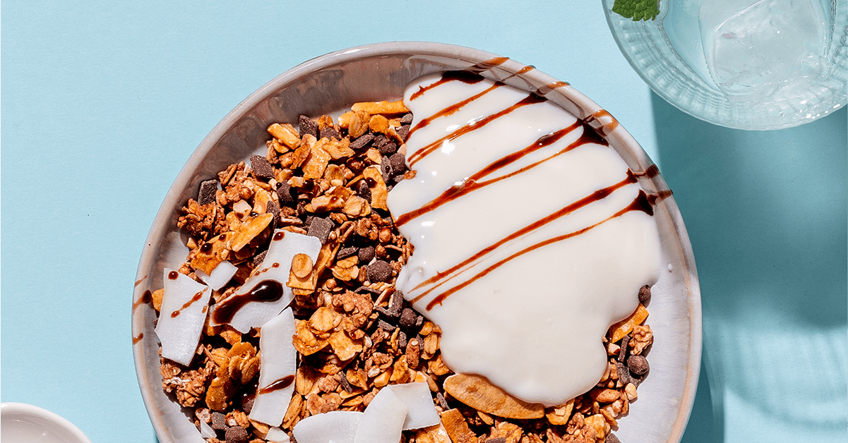 mymuesli Bio Chocolate Hazelnut Almond Granola in Schale mit Joghurt und frischer Kokosnuss