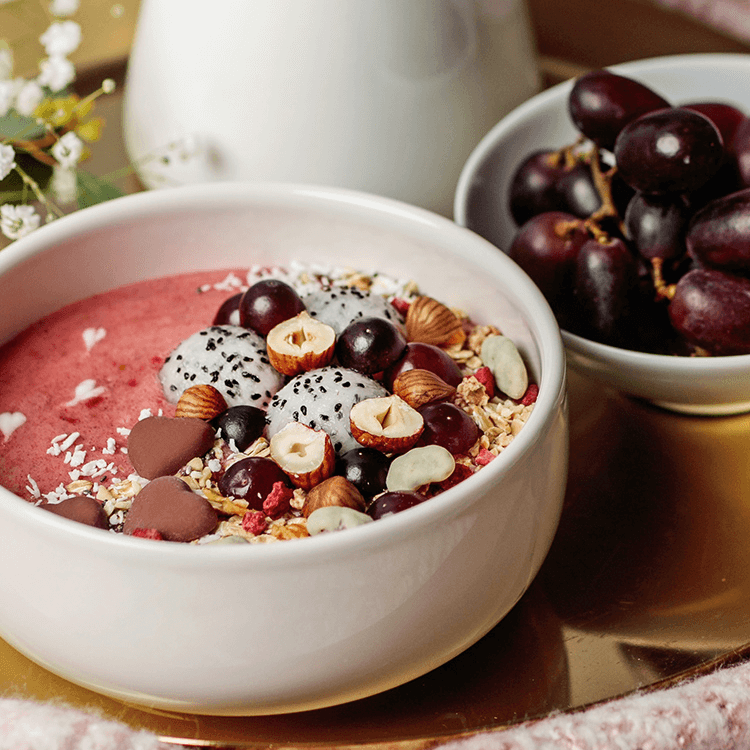 Himbeer-Smoothie-Bowl mit Drachenfrucht und Nüssen als Topping