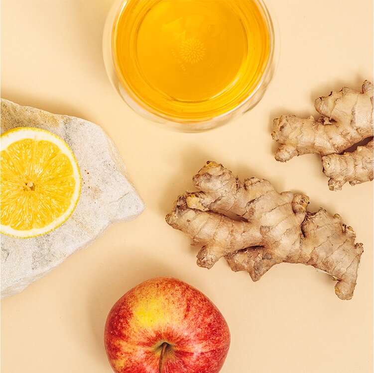Ginger Glow Shots im Glas mit Ingwer, Apfel, Tee und Zitrone daneben