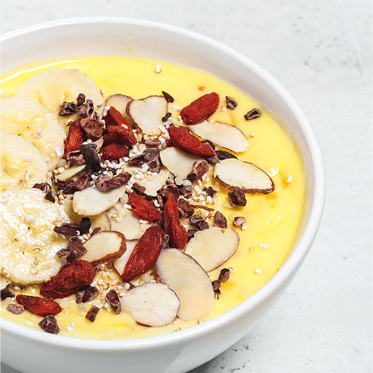 Mango-Kurkuma Bowl in einer Schale mit Bananenscheiben