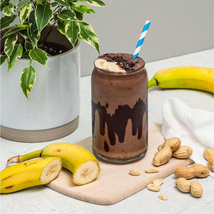 Chocolate Peanut Butter Smoothie mit Bananen und Erdnüssen daneben