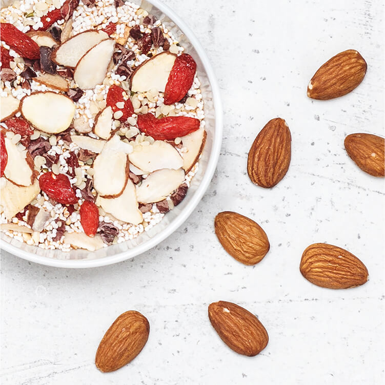 Müsli in einer Schüssel und daneben Mandeln