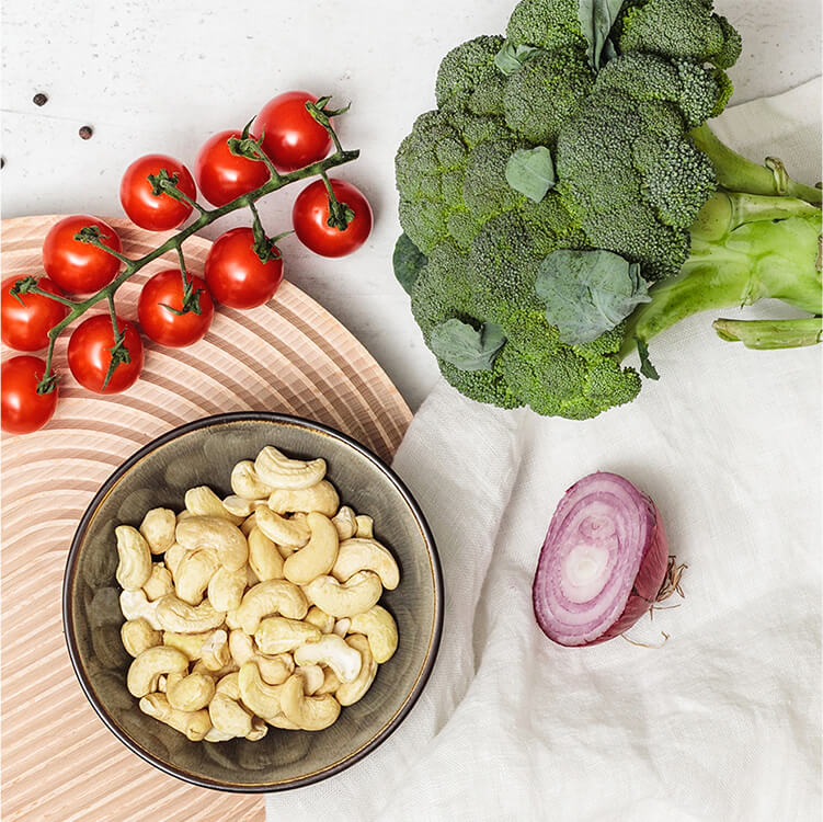 Schüsseln mit Cashews, Tomaten, Brokkoli und Lauchzwiebeln