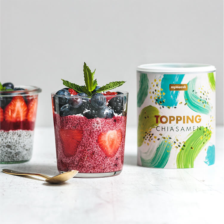 Chia Kokos Pudding mit Beeren im Glas mit einem goldenen Löffel daneben