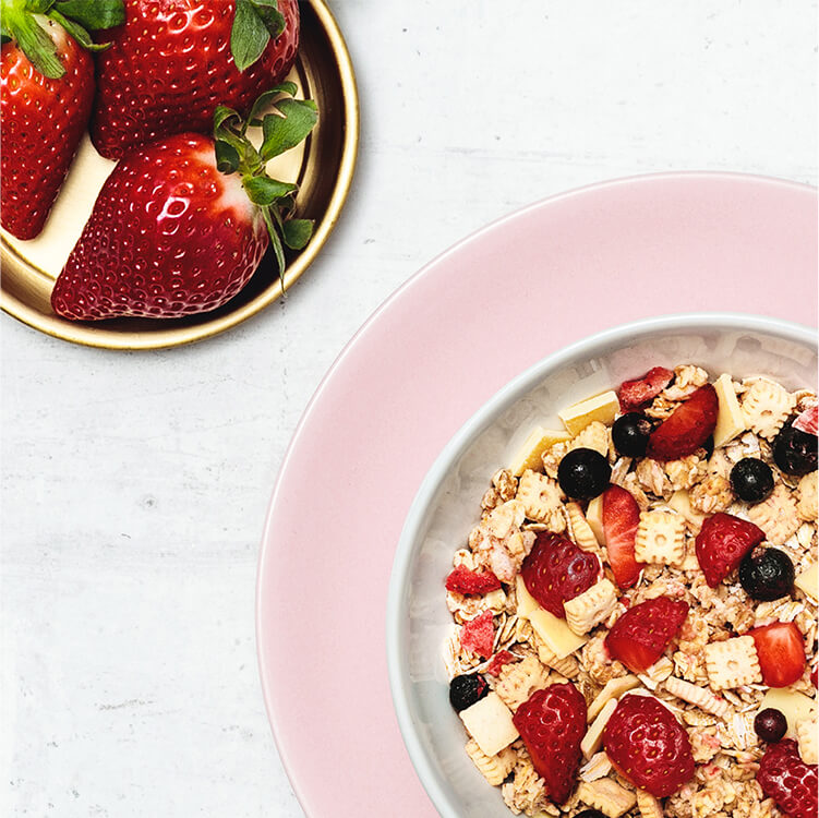 Eine Schüssel mit Müsli und Erdbeeren daneben
