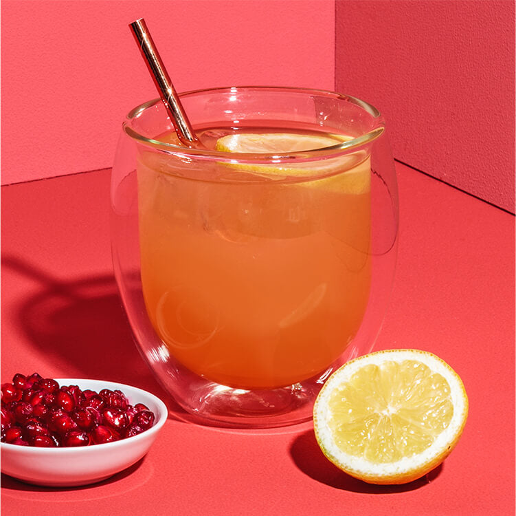 Roi Sour Cocktail mit Granatapfelkernen und Zitrone daneben