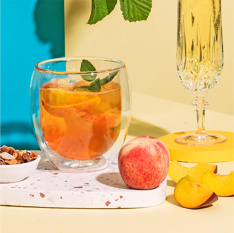 Peachy Bellini in einem Glas und Pfirsiche
