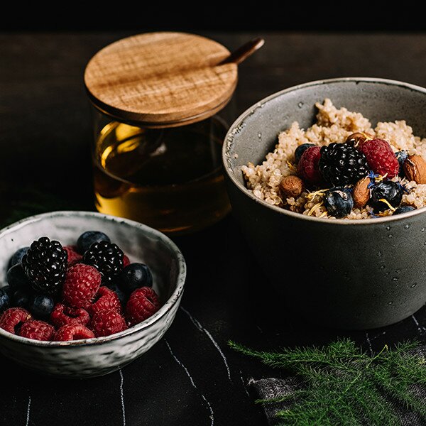 Glutenfreier Porridge in einer Schüssel mit Nüssen und Beeren in einer Schüssel daneben