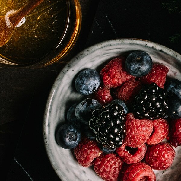 Beeren n einer Schüssel und Honig