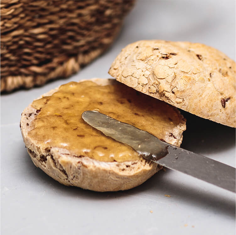 Grünteebrötchen wird mit AUfstrich beschmiert