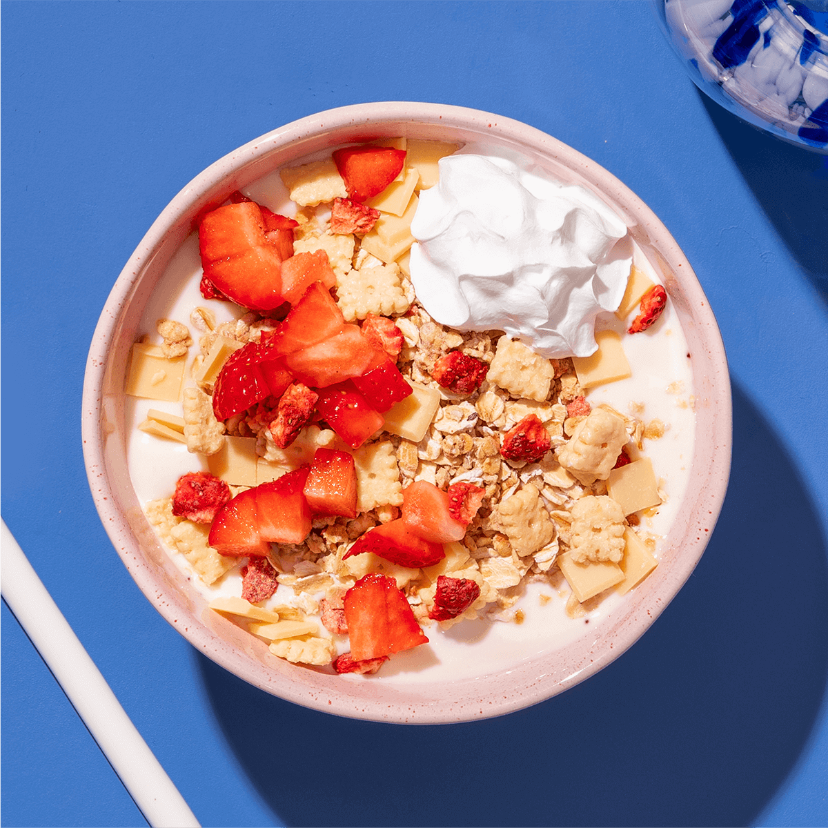 mymuesli Bio Strawberry Cheesecake Müsli in Schale mit frischen Erdbeeren, Milch und Sahne