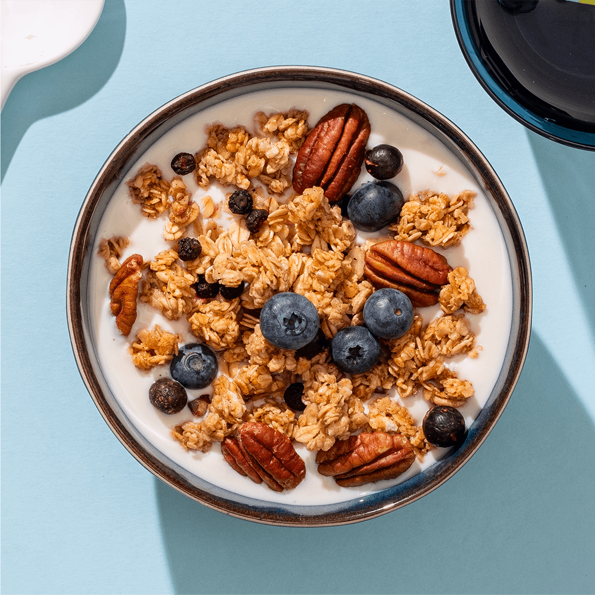 mymuesli Bio Blueberry Cassis Granola in Schale mit Joghurt und frischen Blaubeeren