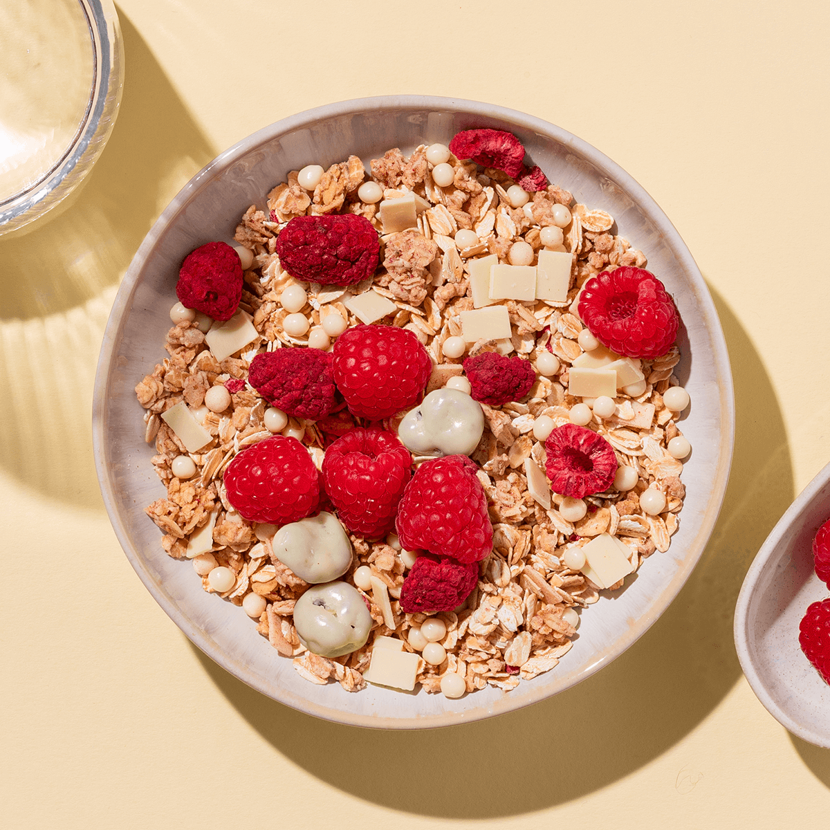 mymuesli Bio Berry White Choc Müsli in Schale mit frischen Himbeeren