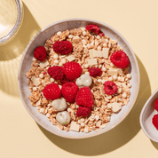 mymuesli Bio Berry White Choc Müsli in Schale mit frischen Himbeeren