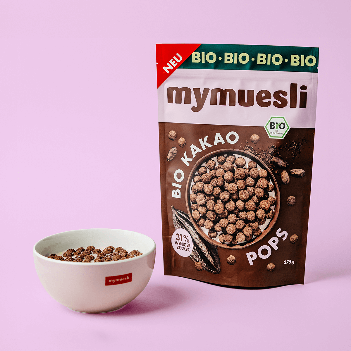mymuesli Bio Kakao Pops Verpackung neben mymuesli Schale mit Milch und Kakao Pops
