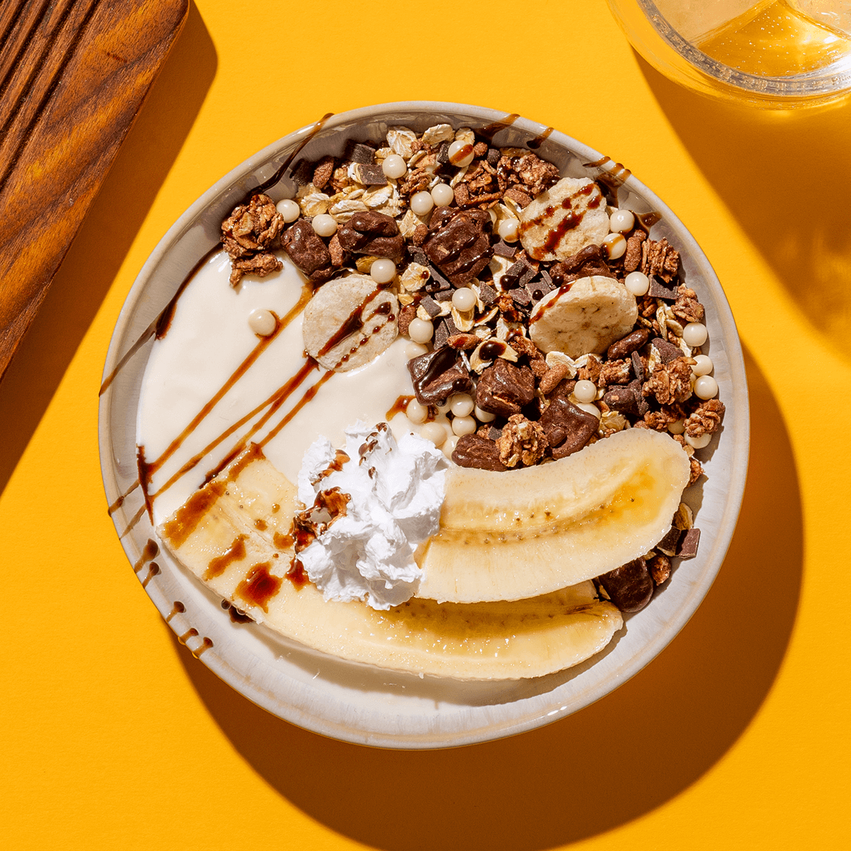 Eine Schale mit Choco Banana Müsli, Joghurt, zwei halbe Bananen und Schokosauce
