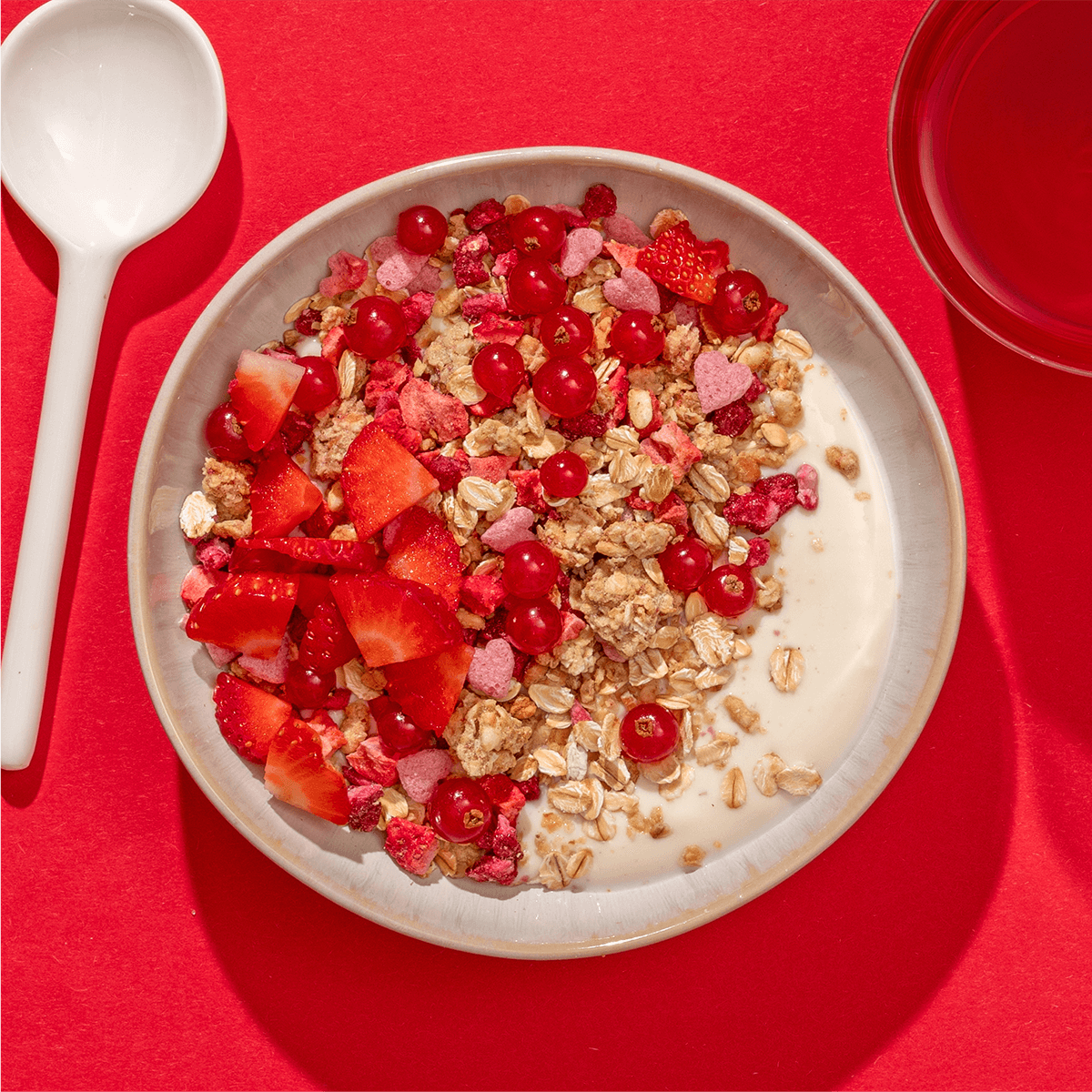 mymuesli Bio Low Sugar Berry Crunch in Schale mit Joghurt, frischen Johannisbeeren und Erdbeeren