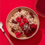 mymuesli Bio Raspberry Coconut Porridge in Schale mit frischen Beeren und Nüssen