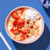 mymuesli Bio Strawberry Cheesecake Müsli in Schale mit Milch, Erdbeeren und Sahne