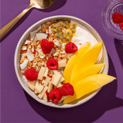 mymuesli Bio Mango Passionfruit Granola mit frischer Maracuja, Mango, Himbeeren und Apfel sowie Joghurt in Schale