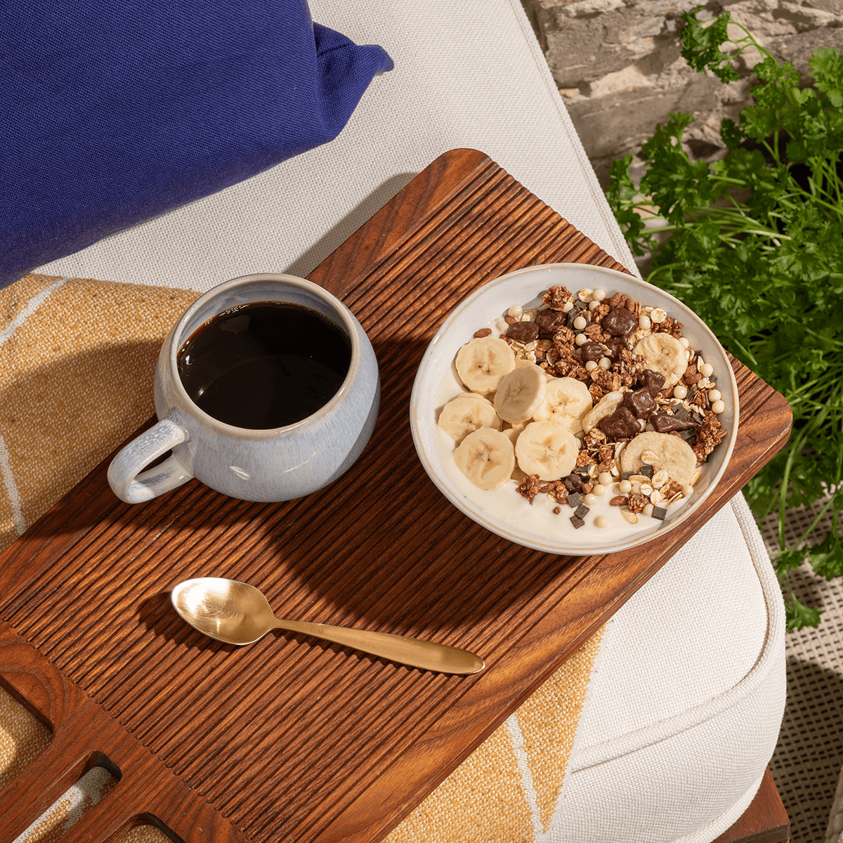 Eine Schale mit Choco Banana Müsli, Joghurt, zwei halbe Bananen und Schokosauce und eine Tasse Kaffee 