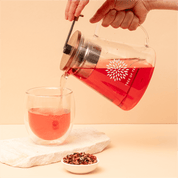 Tree of Tea Glaskanne mit Sieb gießt Tee in ein Teeglas