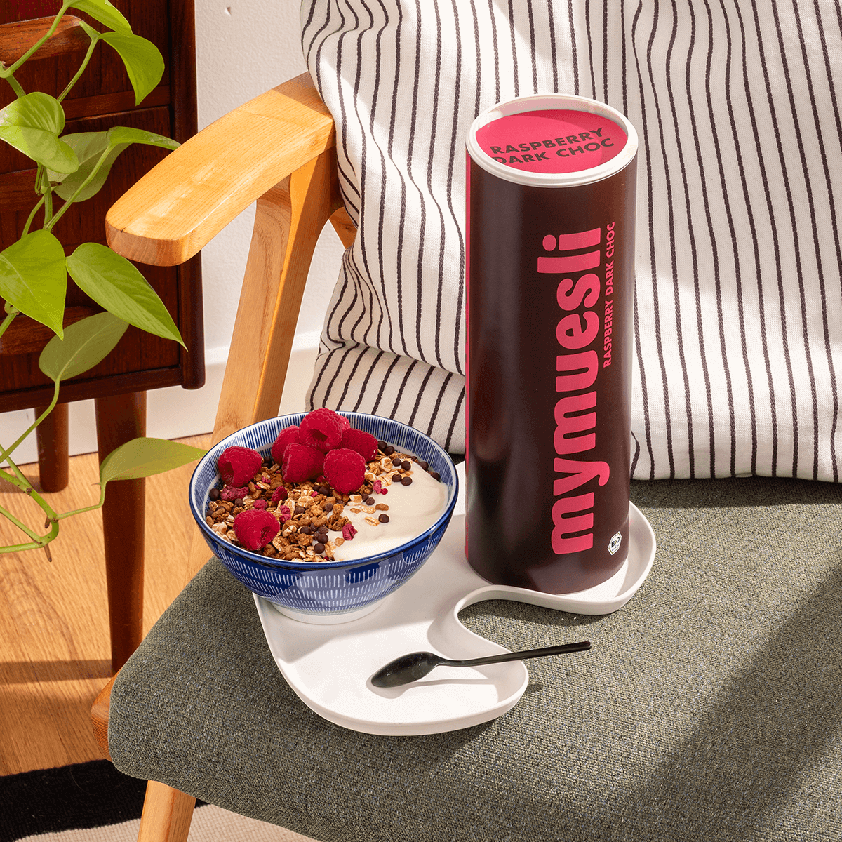 mymuesli Raspberry Dark Choc Dose und daneben eine Schale Müsli mit Himbeeren