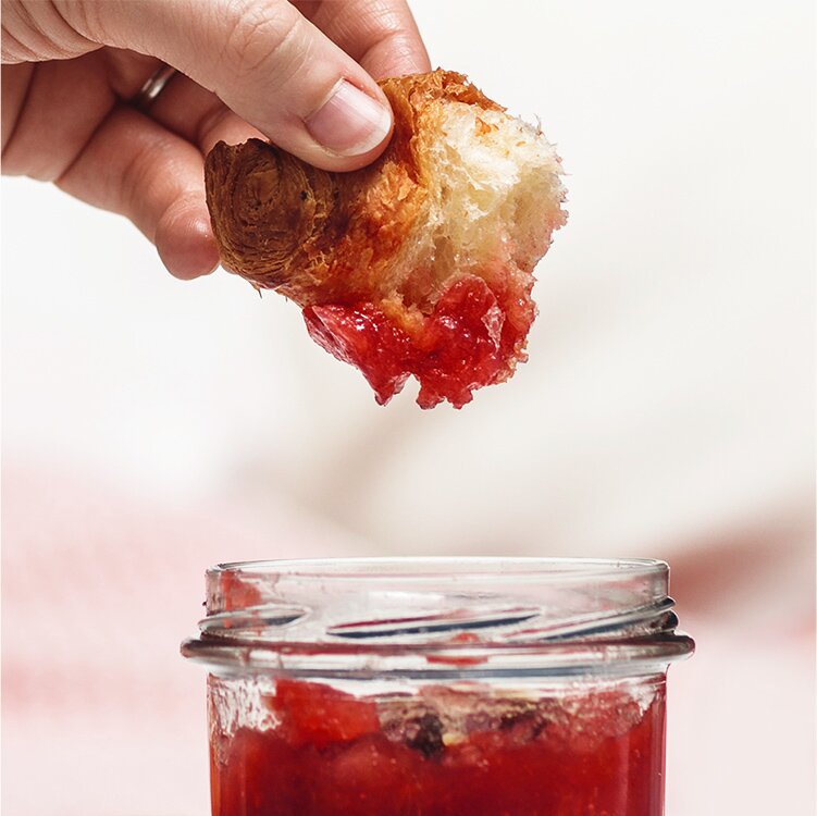 Ruby's Apfel Marmelade in einem Glas, in das ein Croissant gedippt wird