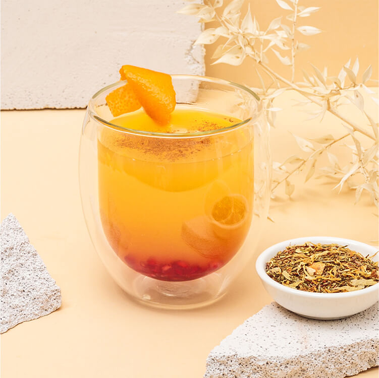 Orangen-Apfelpunsch im Glas und mit Tee in einer Schüssel daneben