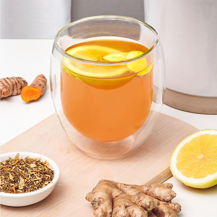 Immunbooster Tee in einem Glas, Zitronen, Tee, Ingwer und Kurkuma daneben