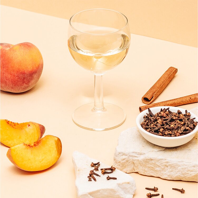 Ein Glas Weißwein, Zimtstangen und Pfirsich