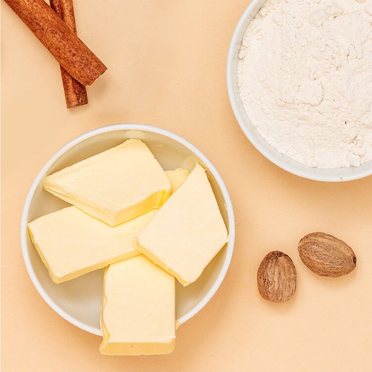 Ein Schälchen Butter und Mehl mit Zimtstangen daneben