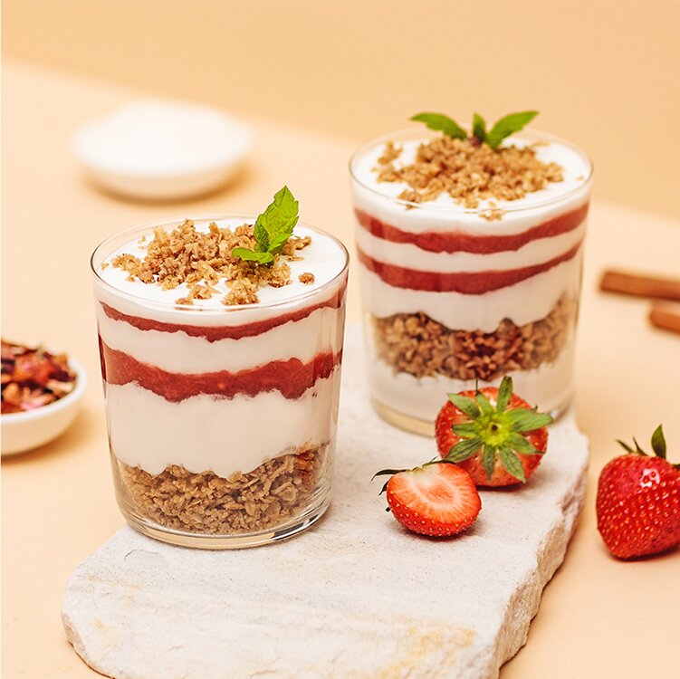 Erdbeer-Schicht-Dessert in einem Glas mit Erdbeeren daneben