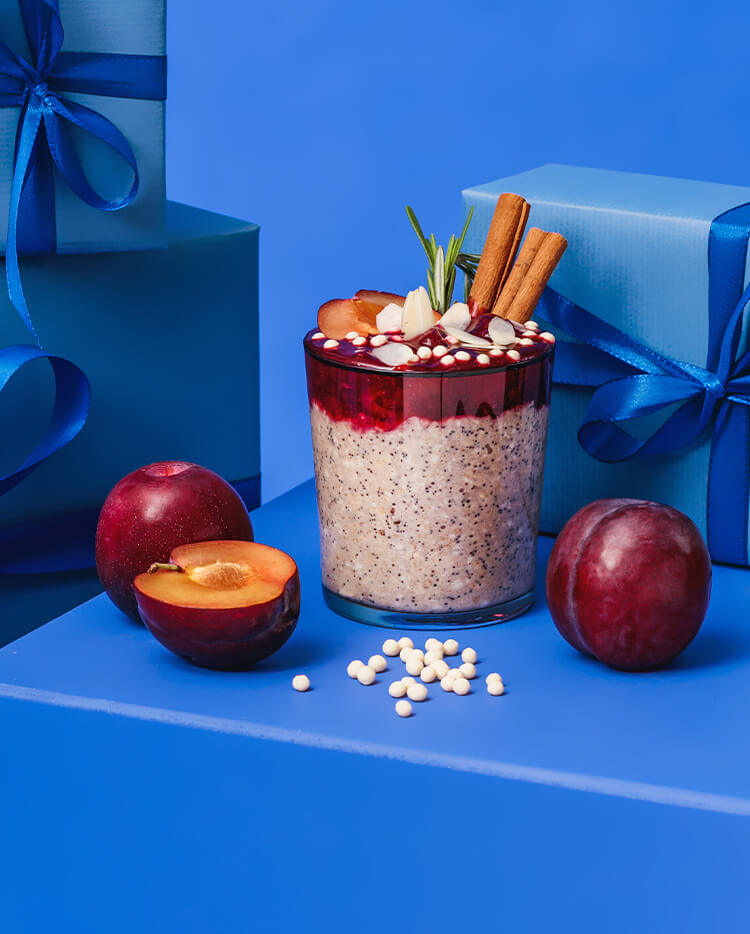 article4b-muesli-porridge-pflaume-mohn.jpg Porridge im Glas huebsch serviert mit festlichem Hintergrund in Blau