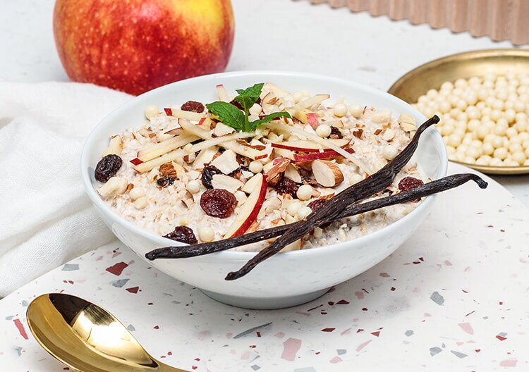 Porridge in der Schale mit frischem Apfel, Nuessen und Vanilleschoten 