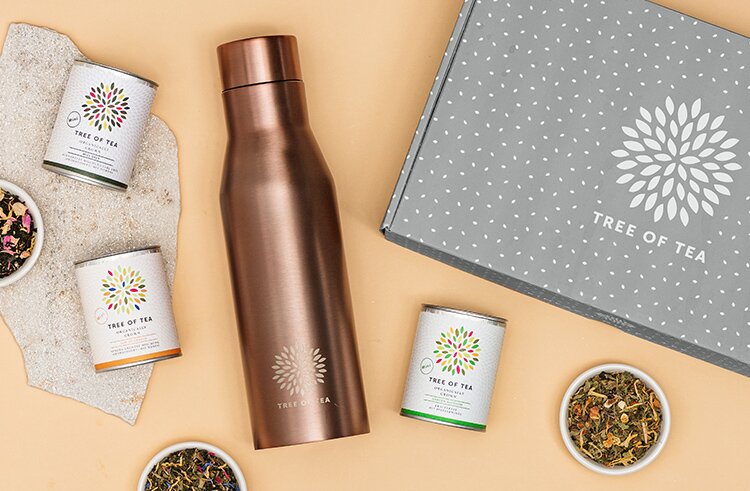 article2a-infuser-thermo-set.jpg Infuser Thermo Flasche fuer Blatttee in Rose neben grauer Geschenkbox mit 3 verschiedenen Bio Tees