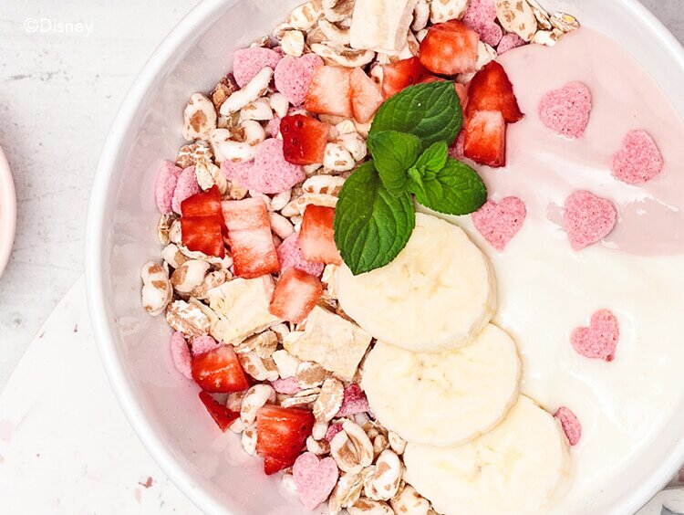 Schale mit Muesli mit Bananenscheiben, Erdbeeren und rosa Weizen Reis Herzen