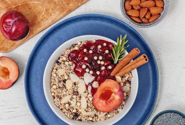 article3b-muesli-porridge-pflaume-mohn.jpg Porridge in der Schuessel mit Zimtstangen, Mandeln, Mohn und Pflaumen