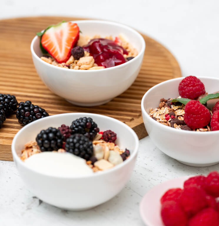 Drei Mueslischalen mit Muesli und frischen Beeren