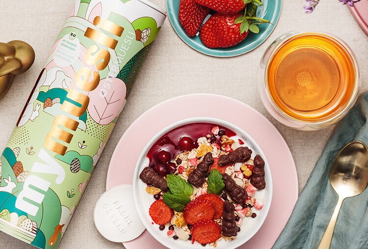 article2b-muesli-osternest.jpg gedeckter Osterfruehstueckstisch mit mymuesli Oster Muesli Mueslischale mit Schokohasen und frischen Erdbeeren