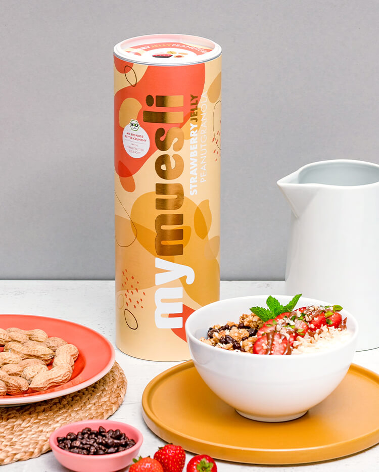 article1a-muesli-strawberry-jelly-peanut-granola.jpg Tisch mit mymuesli Dose und Granola in der Schuessel