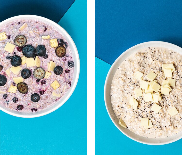 2 Schalen mit Porridge und frischen Blaubeeren und Mini-Butterkeksen und Frischkäseplättchen